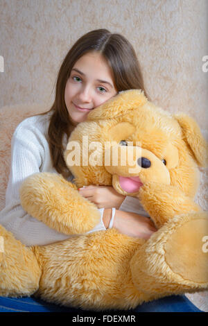 Girl with toy sitting on the couch with a fur coverlet Stock Photo