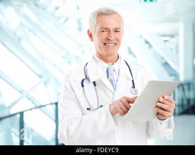 Portrait of male doctor holding digital tablet while standing at clinic. Stock Photo
