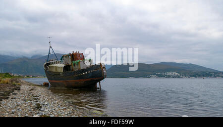 An old wrecked fishing boat grounded on a shingle beach in Kent under ...