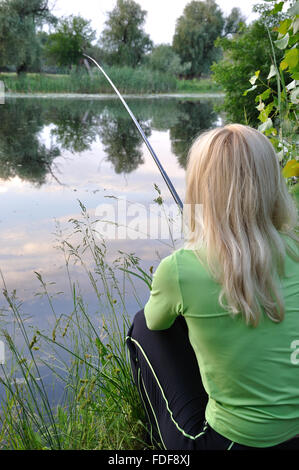 Woman fishing in the river on an old wooden jetty Stock Photo