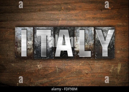The word 'Italy' written in vintage metal letterpress type on an aged wooden background. Stock Photo