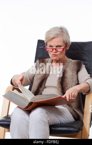 smiling senior old woman reading book in chair Stock Photo