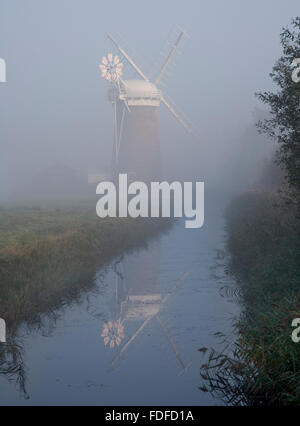 Horsey Windmill and reflectiuon, photographed in Autumn mist along drainage ditch, National trust, Norfolk broads Stock Photo