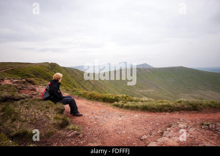 A female walker looking out across the peaks of Pen y fan and Cribyn from Fan Y Big  in the Brecon Beacons, Wales Stock Photo