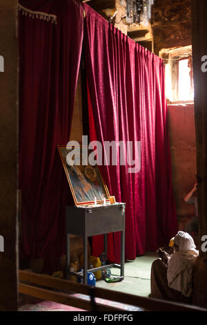 Red curtains catch the low light inside a stone-cut church near Mekele in Ethiopia Stock Photo