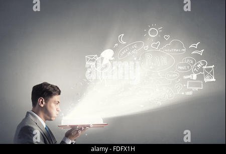 Young businessman with opened book in hands blowing on pages Stock Photo