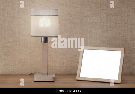 Blank picture frame and lamp on wooden table Stock Photo