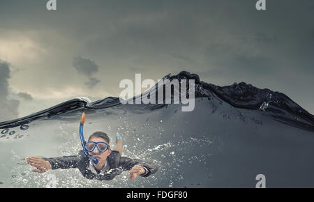 Young businesswoman in suit and diving mask swimming under water Stock Photo