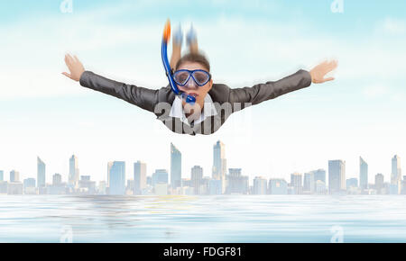 Young businesswoman in suit and diving mask flying in sky Stock Photo