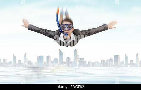 Young businesswoman in suit and diving mask flying in sky Stock Photo