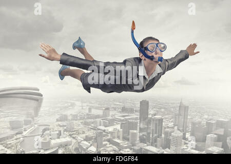 Young businesswoman in suit and diving mask flying in sky Stock Photo