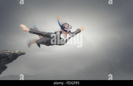 Young businesswoman in suit and diving mask flying in sky Stock Photo