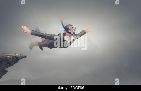 Young businesswoman in suit and diving mask flying in sky Stock Photo