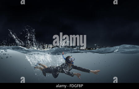 Young businesswoman in suit and diving mask swimming under water Stock Photo