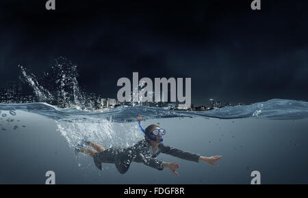 Young businesswoman in suit and diving mask swimming under water Stock Photo