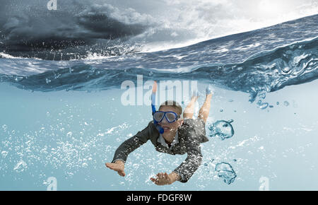 Young businesswoman in suit and diving mask swimming under water Stock Photo