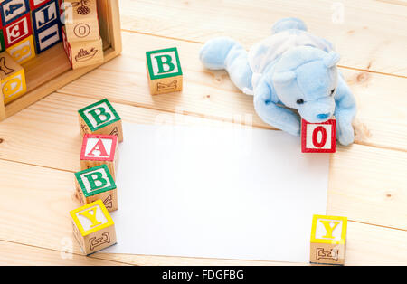 Baby announcement Invitation a blue toy bear spelling the words baby boy with wooden toy blocks on pine wood floor background Stock Photo