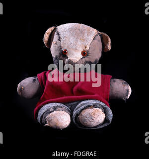 Vintage loved and worn soft toys; monkeys, bears, badgers and rabbits shot individually on a black background in the studio. Stock Photo