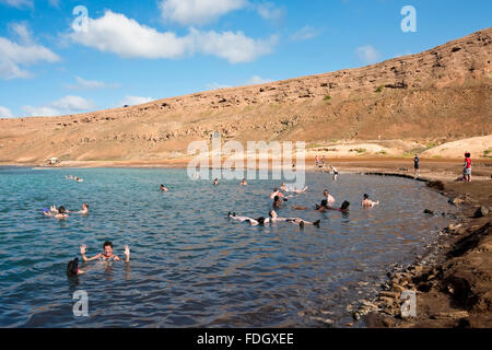 Horizontal view of tourists floating in the salt crater on Sal, in Cape Verde. Stock Photo