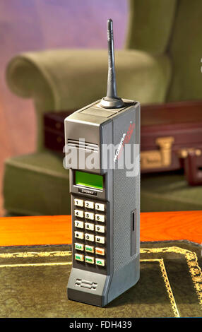 1987 Nokia Mobira Cityman 1320 first generation hand mobile cell phone  with 1980's Parker Knoll armchair and 80's business briefcase in background Stock Photo