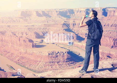 Retro toned female tourist drinking water by canyon, USA. Stock Photo