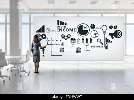 Elegant businesswoman in modern office interior against window panoramic view drawing on banner Stock Photo