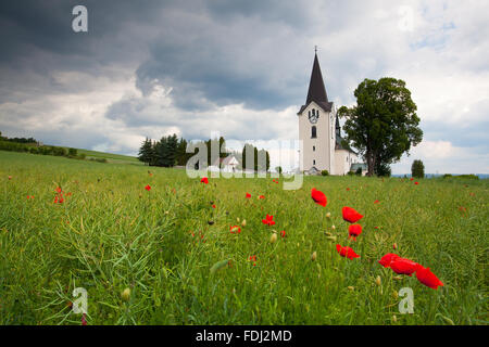 Lonely church in the middle poppy field before heavy storm Stock Photo