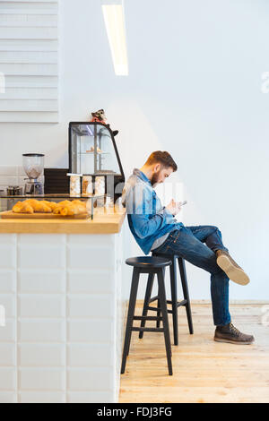 Casual young man using smartphone in cafe Stock Photo