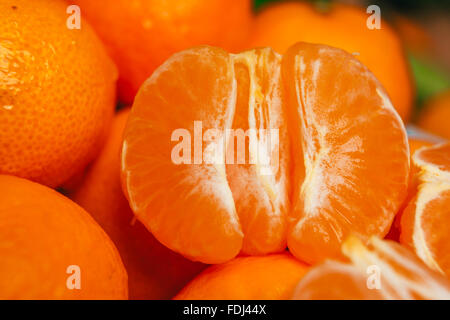 fresh peeled  tangerine segments close up on a background of orange mandarins Stock Photo