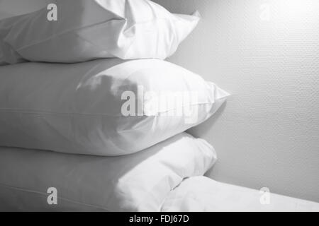 Pile of white pillows lying on the empty bed Stock Photo