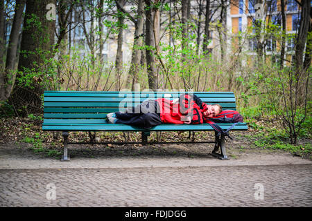 Homeless man sleeping on park bench in Berlin Stock Photo