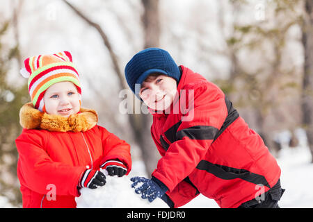 Cute boy and girl building snowman in winter park Stock Photo