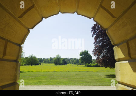 View from one of the rusticated arches of the basement, under the loggia, acroos the lawn on the West front at Basildon Park, built 1776-83 by John Carr for Francis Sykes, at Lower Basildon, Reading, Berkshire. Stock Photo