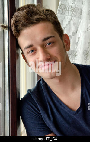 Eighten years old turkish young man lean on window smiling softly Stock Photo