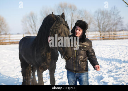 The man strokes the horse's head in winter Stock Photo