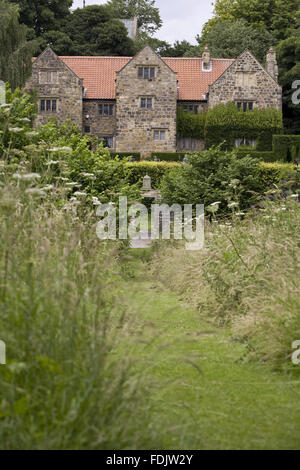 A view through a mown path to the seventeenth-century manor house, Washington Old Hall, Tyne & Wear. The manor retains parts of the original medieval house, home of the ancestors of George Washington. Stock Photo