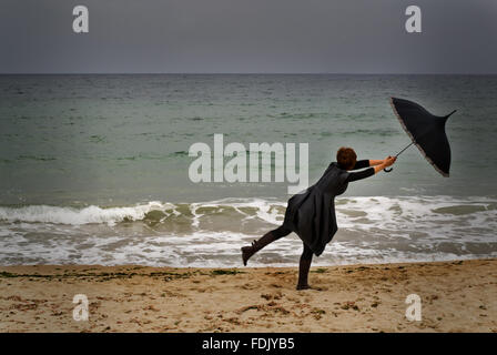 Woman with umbrella on beach on a Windy day Stock Photo