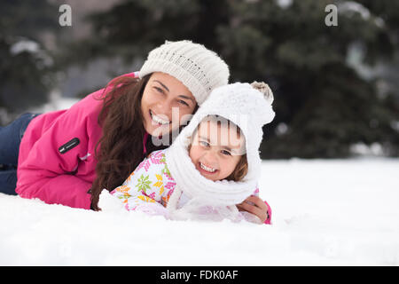 Happy mother and daughter lying in the snow Stock Photo