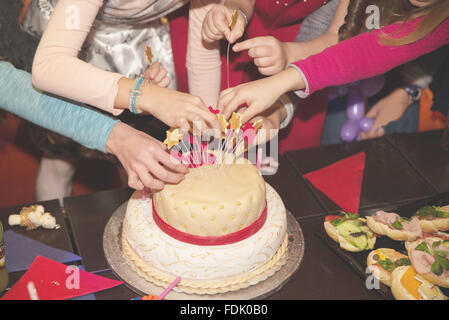 Four children decorating birthday cake Stock Photo