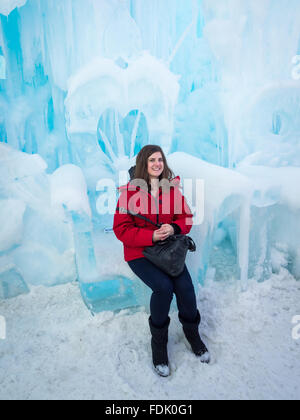 A pretty brunette girl sits on a throne sculpted from ice at the Ice Castle in Hawrelak Park, Edmonton, Alberta, Canada. Stock Photo