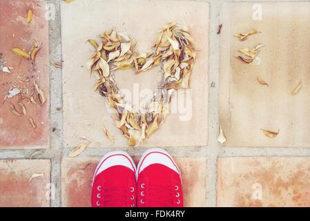 Feet standing in front of heart shape made of leaves Stock Photo