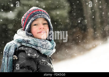 Smiling boy standing in the forest in the snow Stock Photo