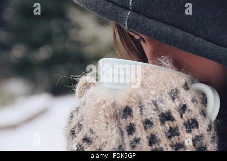 Girl standing outdoors in the snow drinking tea Stock Photo
