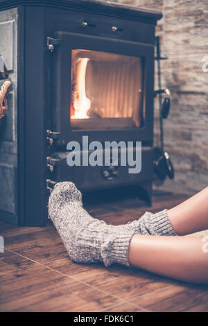 Woman sitting  in front of a wood burning stove Stock Photo