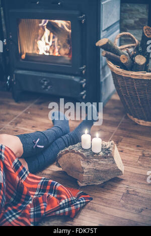 Woman sitting in front of a fireplace Stock Photo