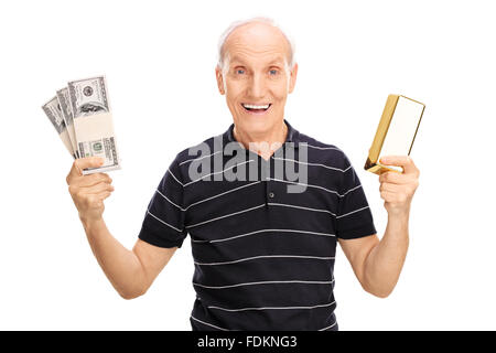 Joyful senior holding few stacks of money and a gold bar isolated on white background Stock Photo