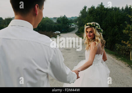 bride leads groom on the road Stock Photo