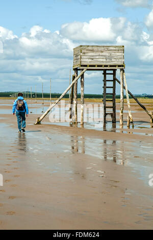 Hiker, safety tower and wooden poles, Pilgrim's Way, Holy Island, England, United Kingdom Stock Photo