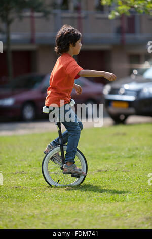 Boy balancing on a unicycle in the park Stock Photo