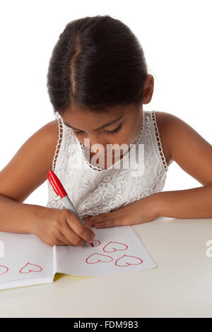 Young teenage girl drawing little hearts in her note book on white background Stock Photo